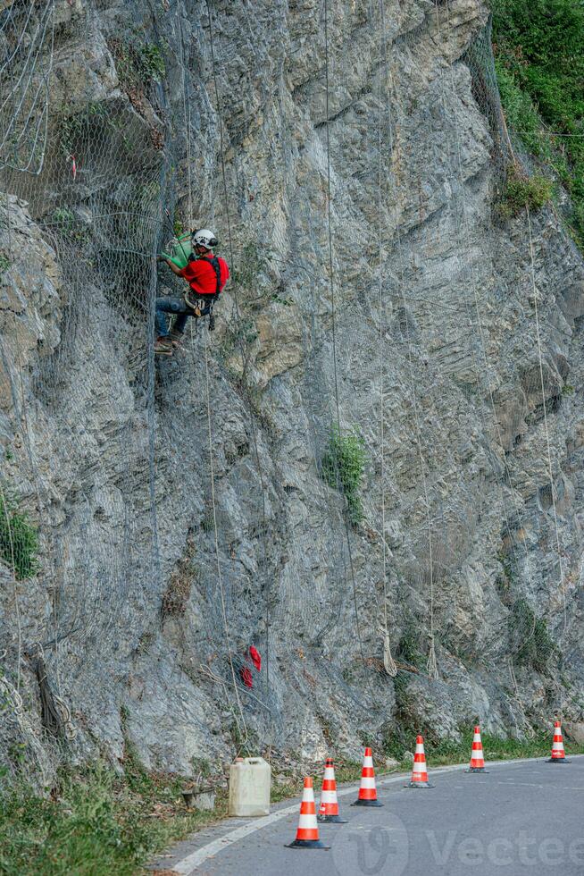 Climber placing safety nets to avoid falling rocks photo