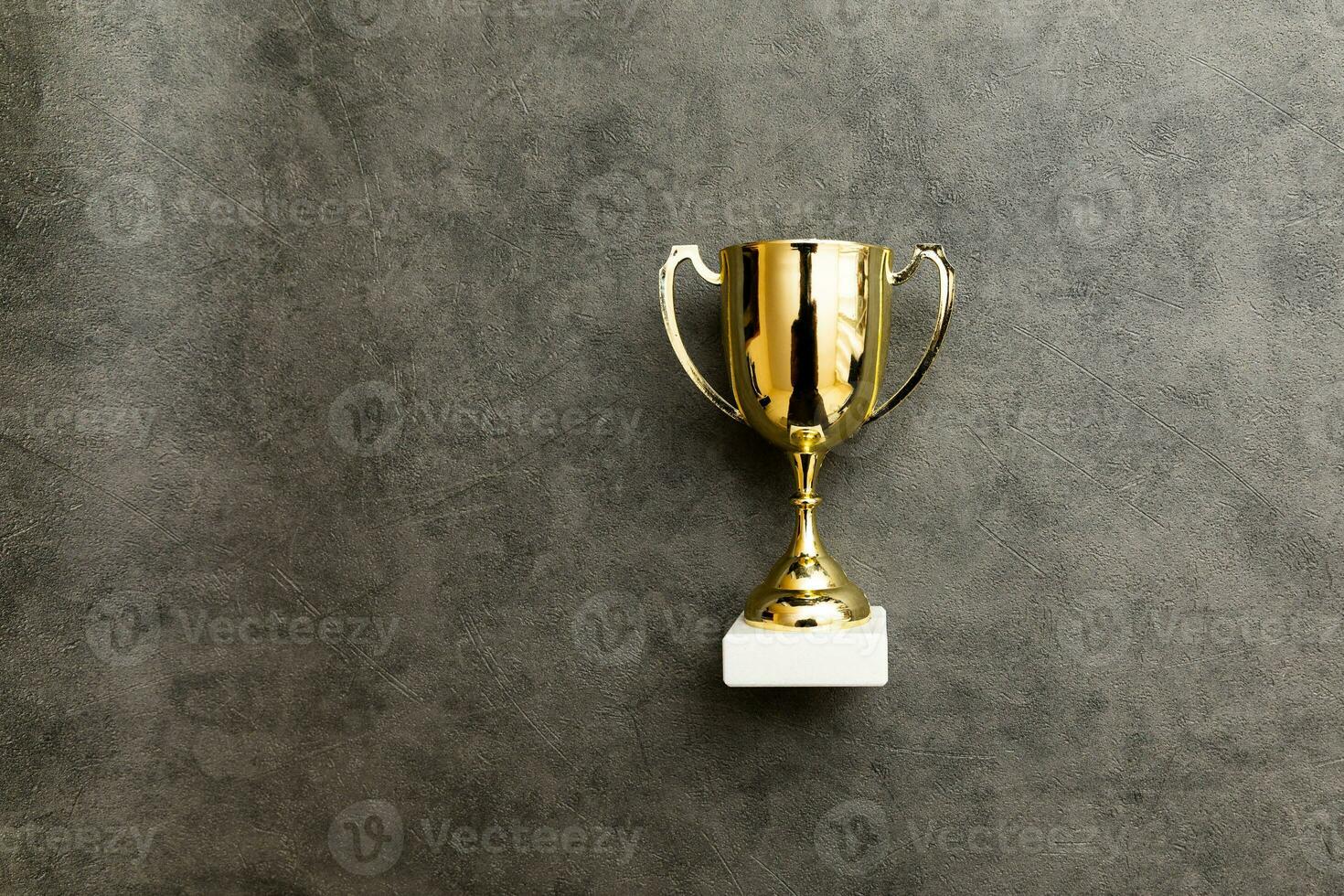 Simply flat lay design winner or champion gold trophy cup on concrete stone grey background. Victory first place of competition. Winning or success concept. Top view copy space. photo