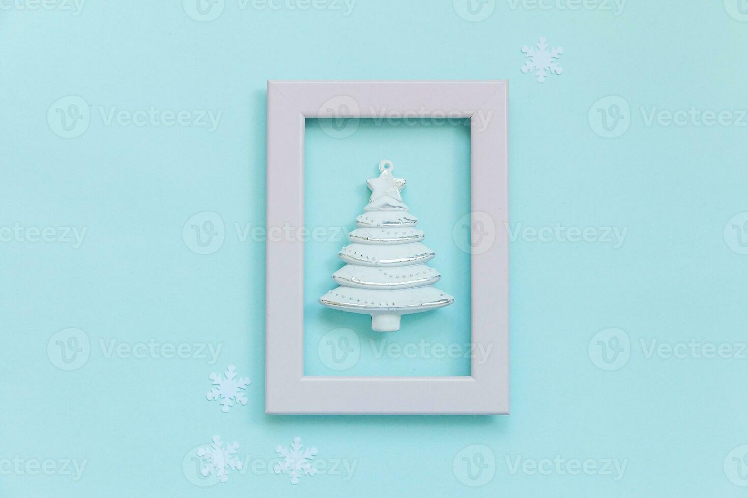 Simply minimal composition winter objects ornament fir tree in pink frame isolated on blue pastel trendy background photo
