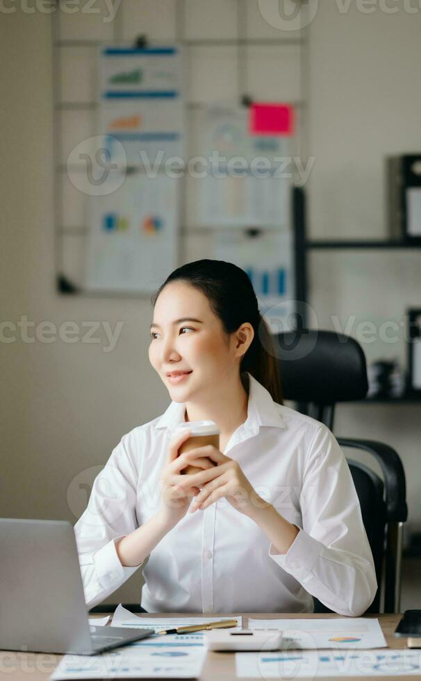 Asian businesswoman working in the office with working notepad, tablet and laptop documents photo