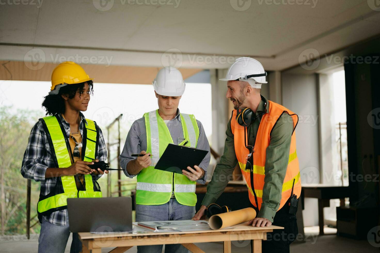 Contractor and architect looking at plan, tablet, laptop and talking about working on big project. Building in construction process interior. team work photo