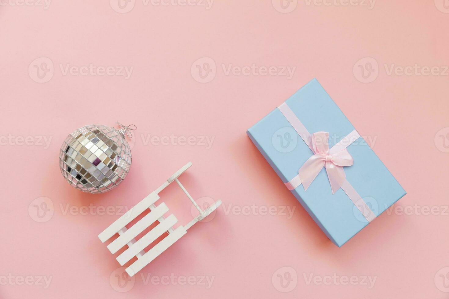 Simply minimal composition winter objects ornament ball sled gift box isolated on pink pastel trendy background photo