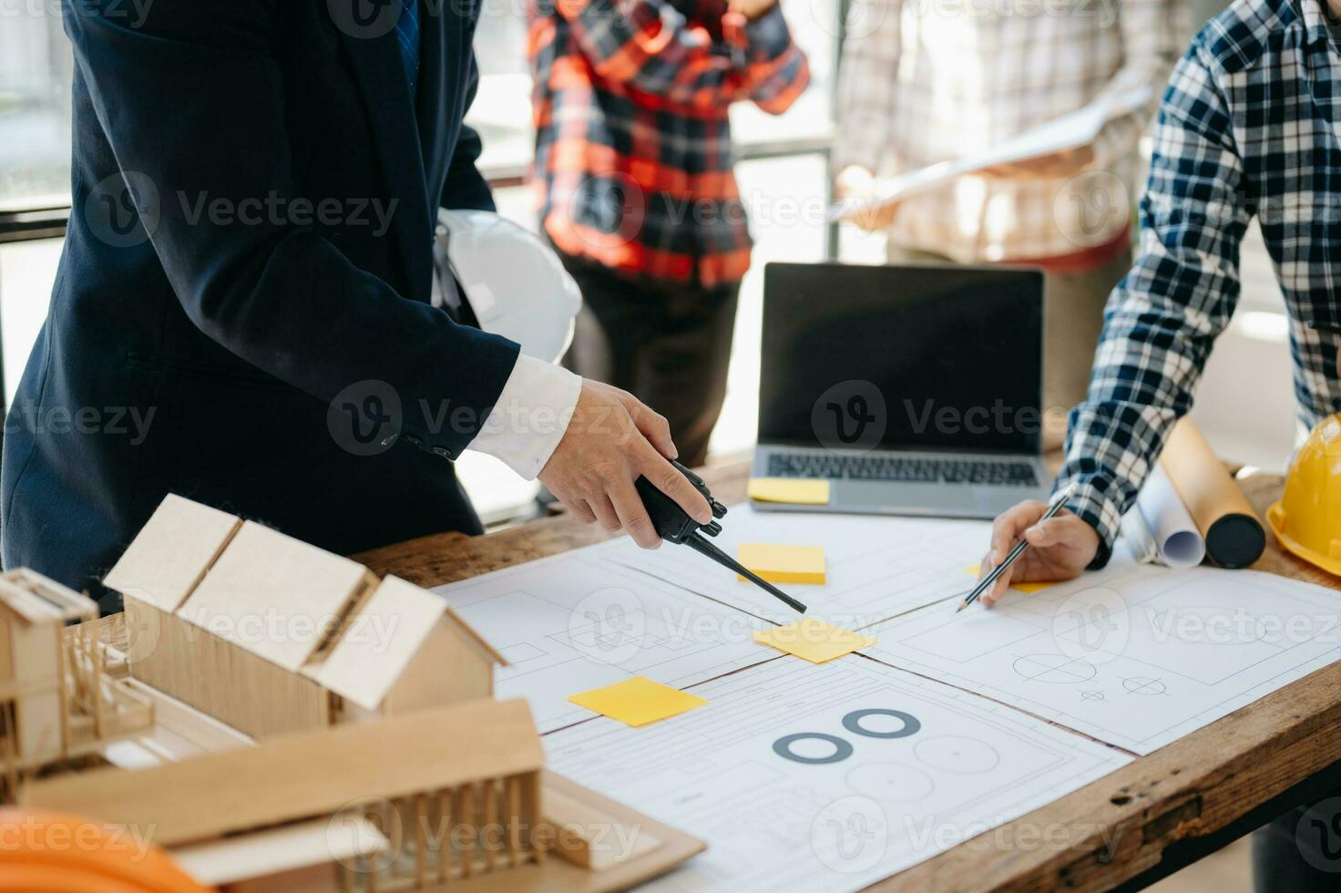 Three colleagues discussing data working and tablet, laptop with on on architectural project at construction site at desk in office photo
