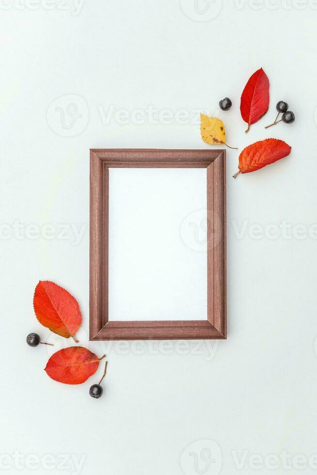 Autumn floral composition. Vertical photo frame mockup chokeberry rowan berries colorful leaves on white background. Fall natural plants ecology fresh wallpaper concept. Flat lay top view, copy space