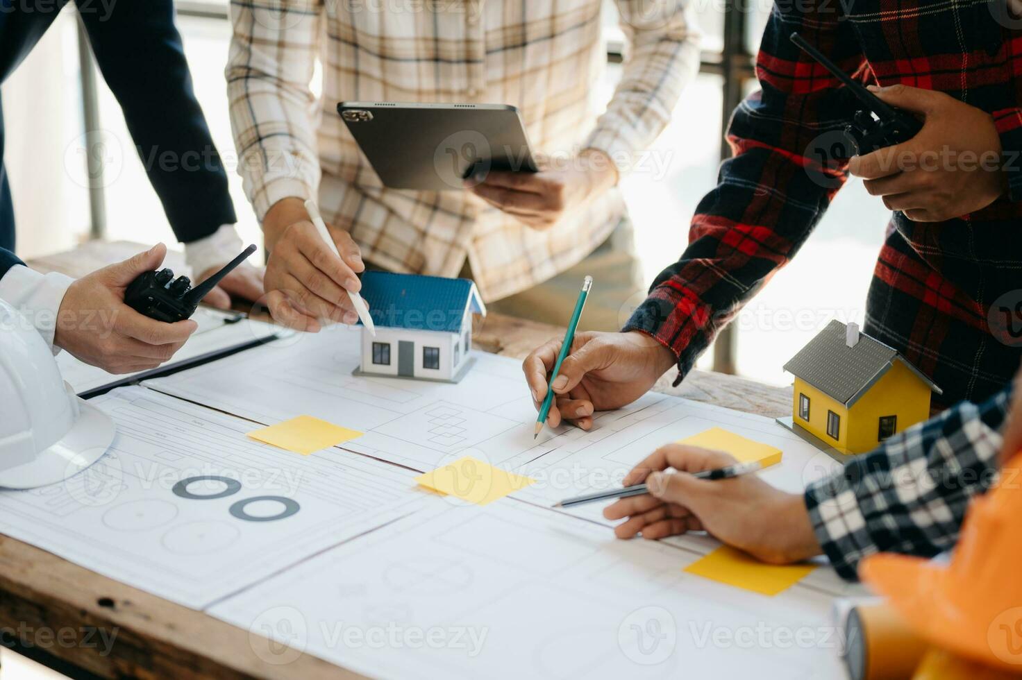 Three colleagues discussing data working and tablet, laptop with on on architectural project at construction site at desk in office photo