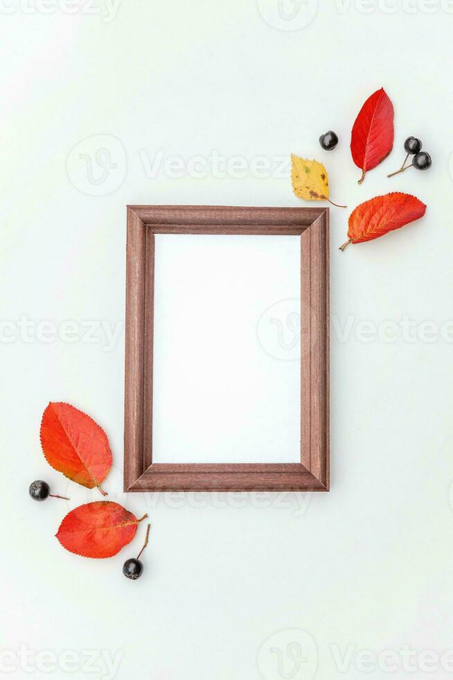 Autumn floral composition. Vertical photo frame mockup chokeberry rowan berries colorful leaves on white background. Fall natural plants ecology fresh wallpaper concept. Flat lay top view, copy space