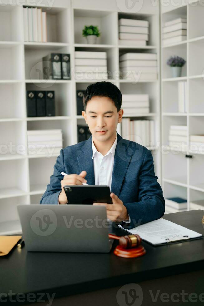 Attractive young lawyer in office Business man and lawyers discussing contract papers laptop and tablet with brass scale on  desk in modern office. Law, legal services, advice, photo