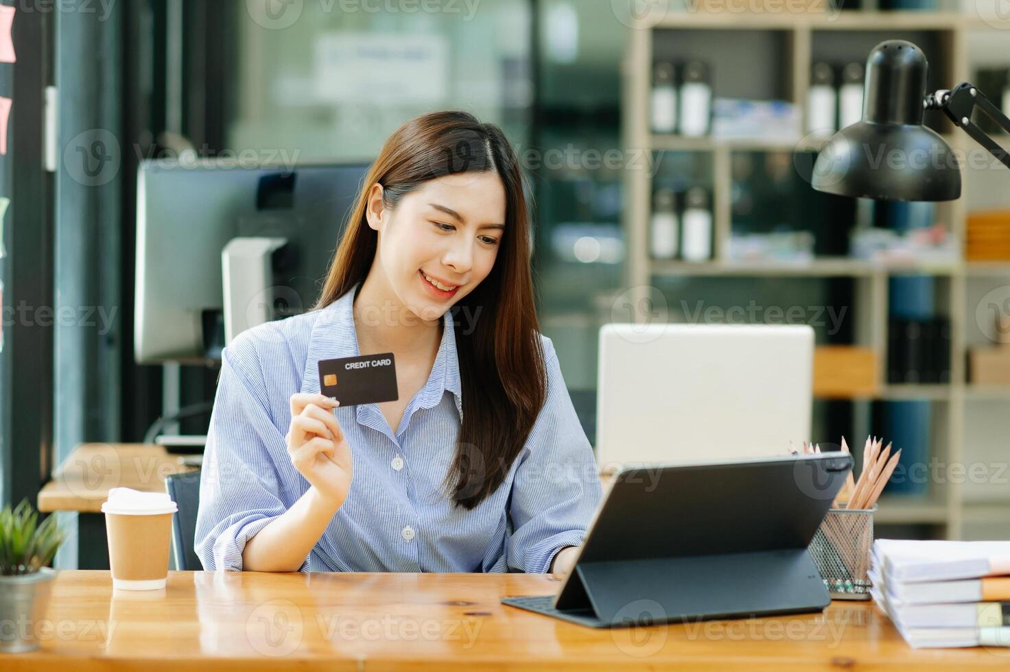 Asian Woman using smart phone for mobile payments online shopping,omni channel,sitting on table,virtual icons graphics interface screen in morning light photo