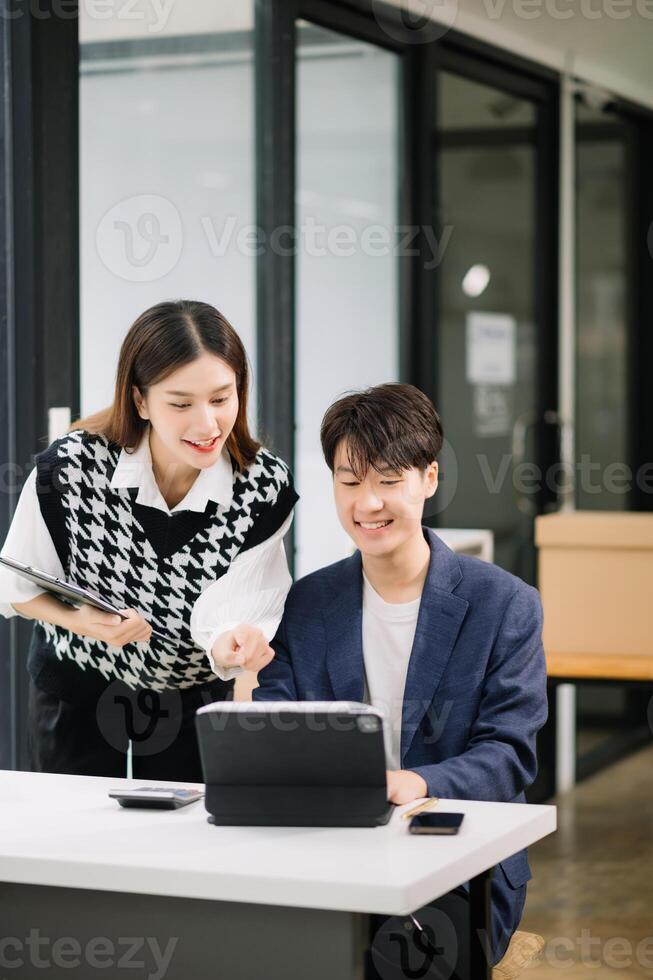 Two Asian business workers talking on the smartphone and using laptop at the modern office. photo