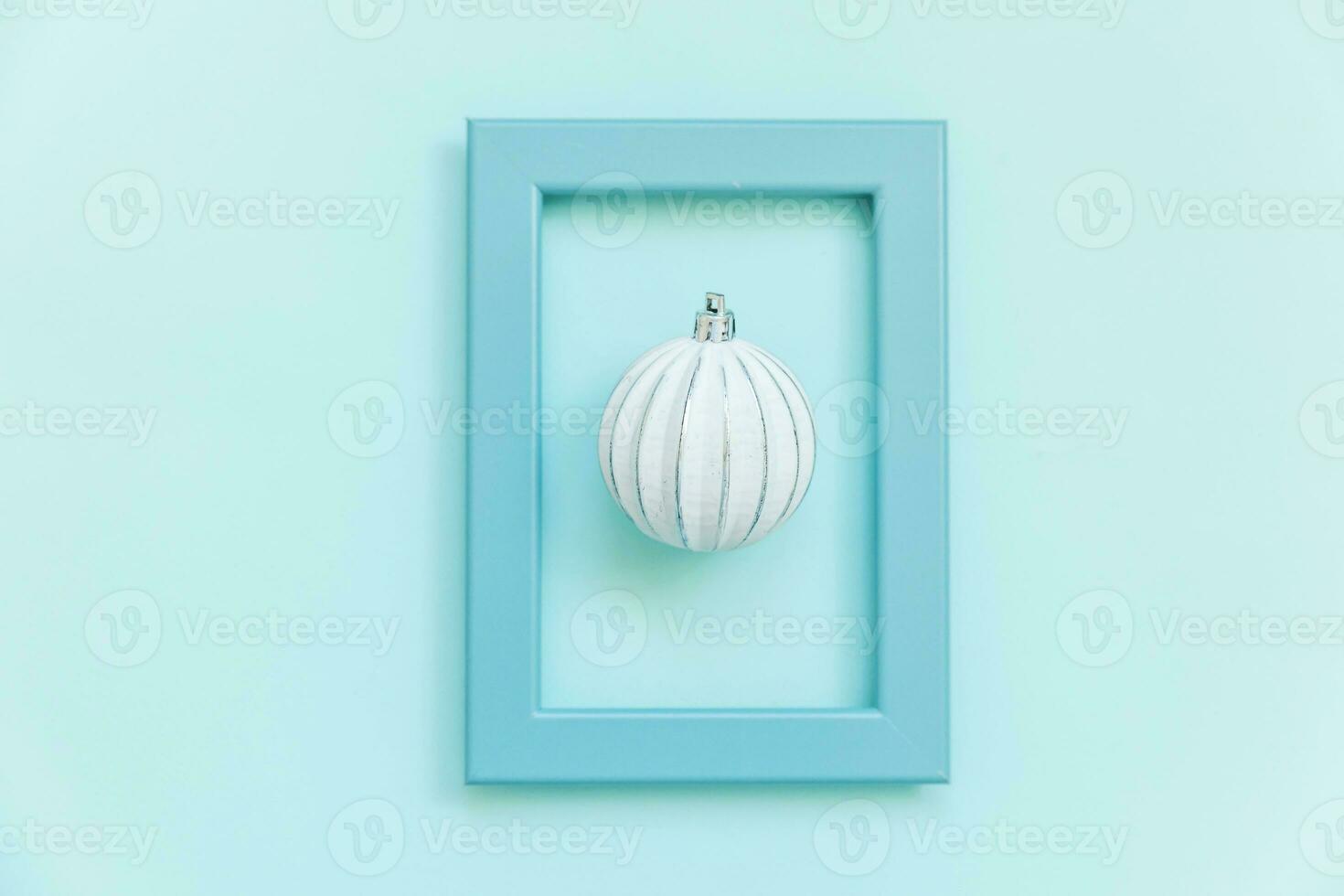 Simply minimal composition winter objects ornament ball in blue frame isolated on blue pastel trendy background photo