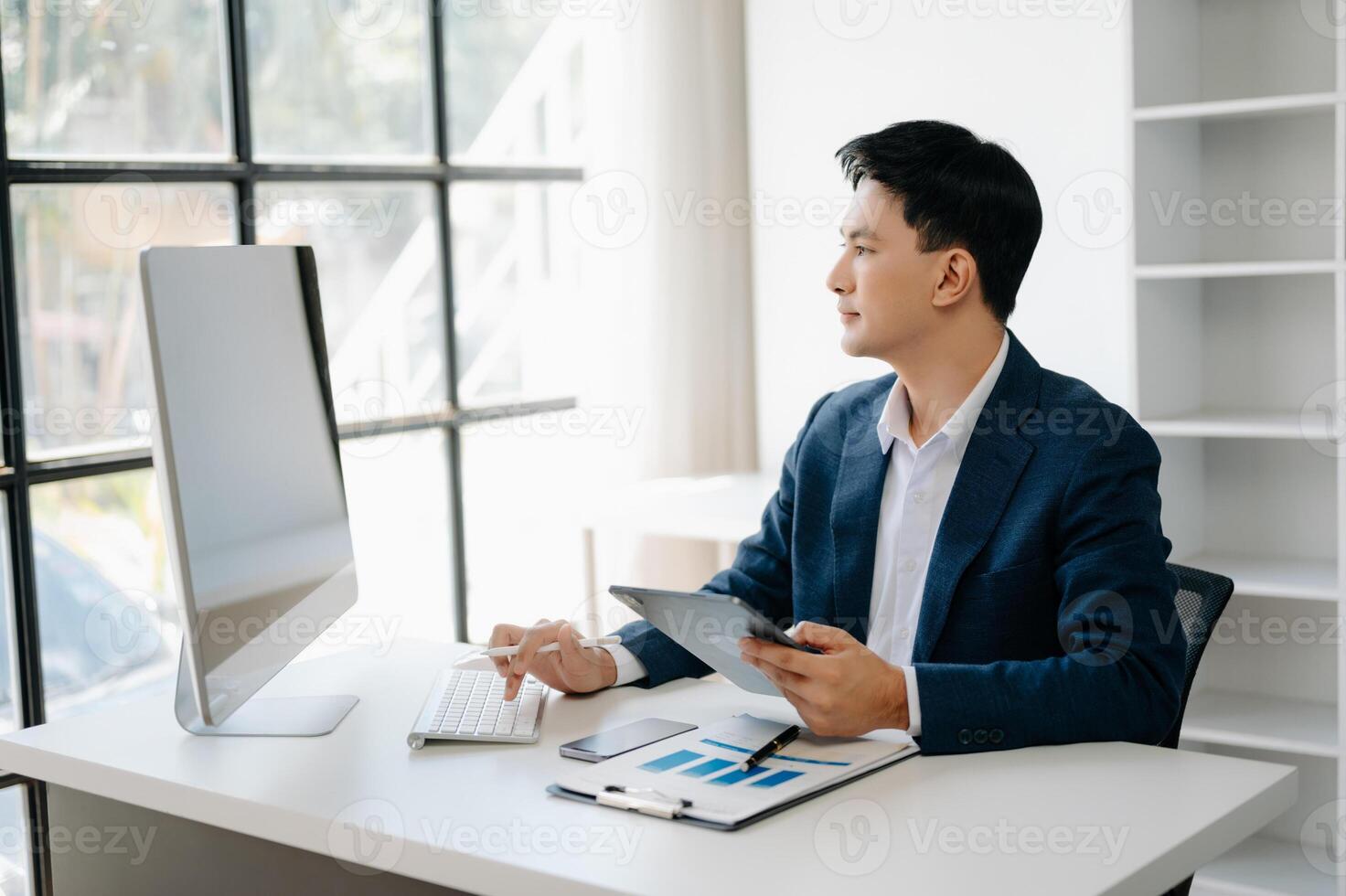 Business man using tablet and laptop for doing math finance on an office desk, tax, report, accounting, statistics, and analytical research concept in office photo