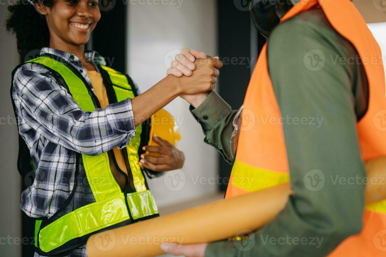 Construction team shake hands greeting start new project plan behind yellow helmet on desk in office center to consults about their building project. photo