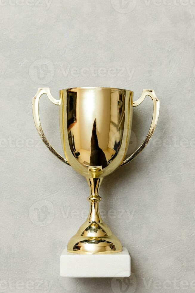 Simply flat lay design winner or champion gold trophy cup on concrete stone grey background. Victory first place of competition. Winning or success concept. Top view copy space. photo