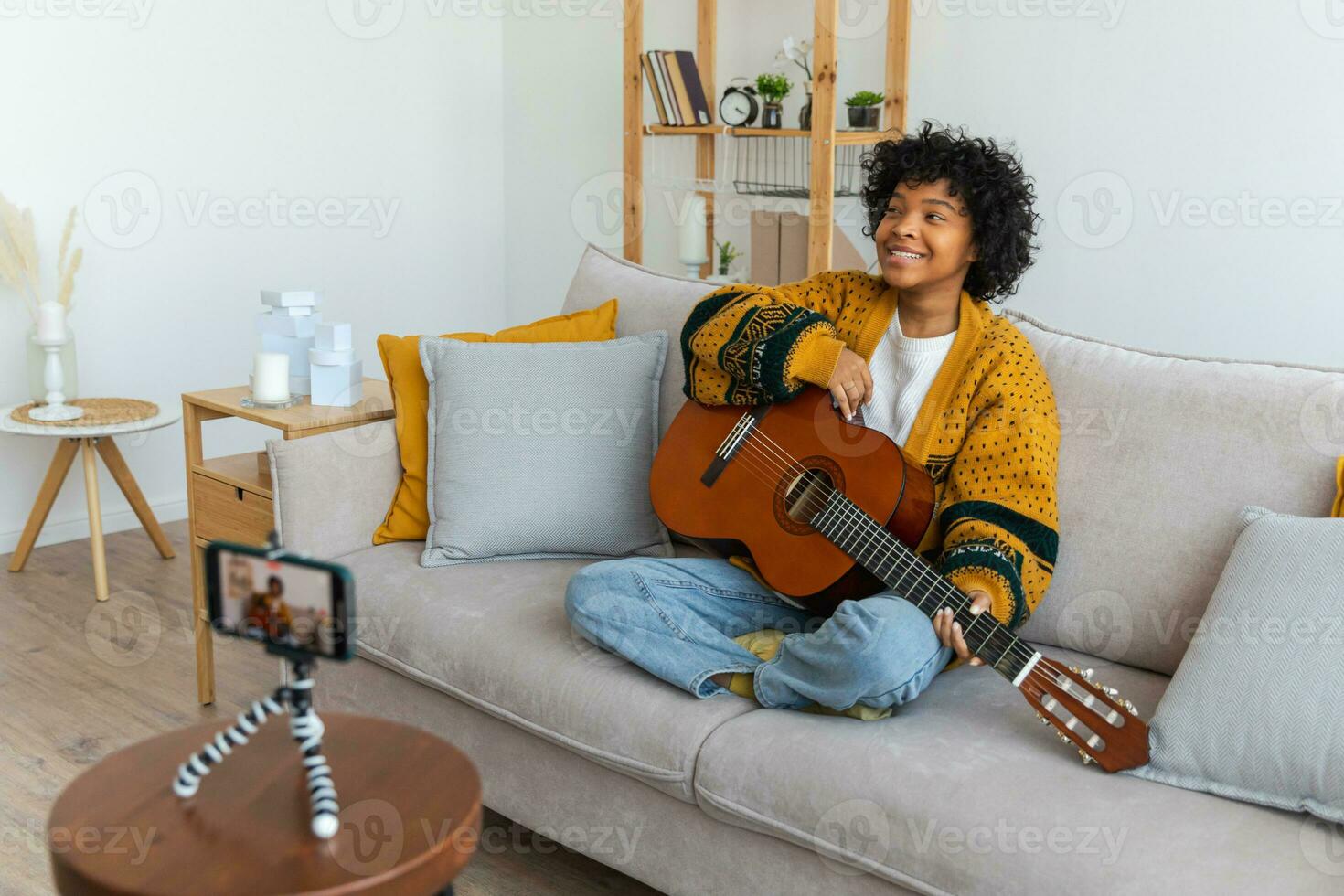 Blogger guitarist. African american girl blogger playing guitar talking to webcam recording vlog. Social media influencer woman streaming at home indoors. Music content creator broadcast tutorial. photo