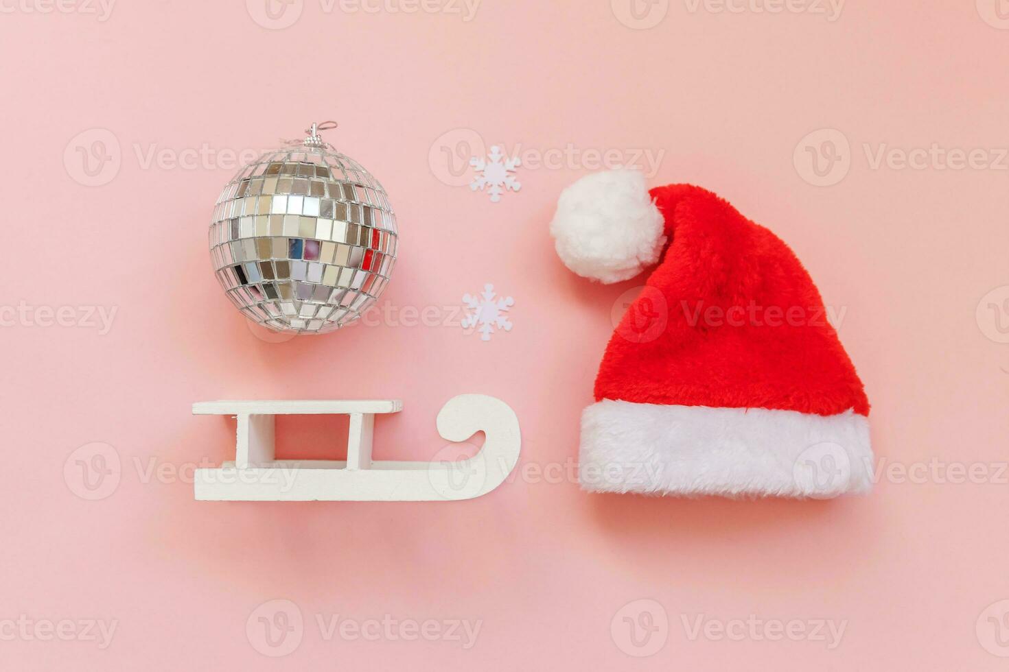 Simply minimal composition winter objects ornament ball Santa hat sled isolated on pink pastel trendy background photo