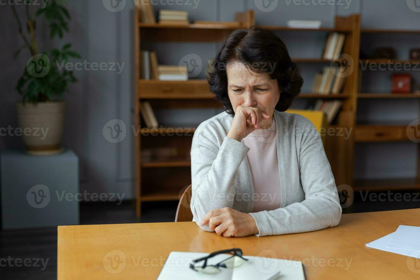 Sad tired ill sick lonely disappointed older senior woman sitting at home alone. Unhappy mature grandmother experiencing grief relative death bad news. Stressed elder lady suffering from loneliness. photo