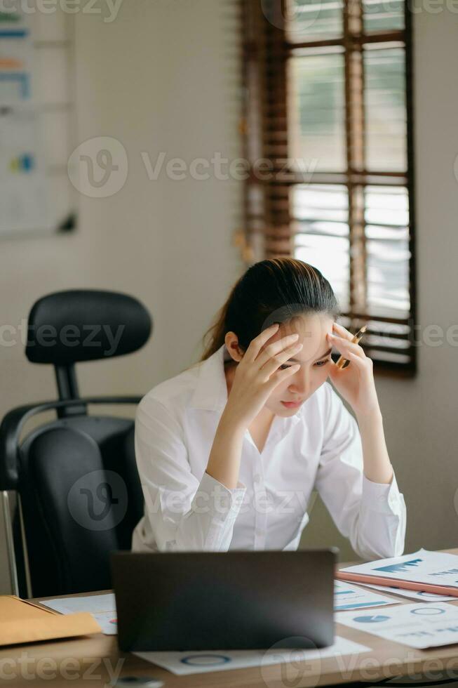 Asian business woman is stressed, bored, and overthinking from working on a tablet at the  office. photo