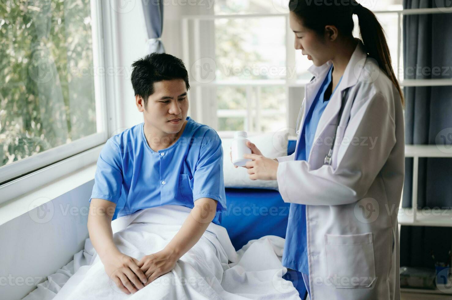 Doctor and young male patient who lie on the bed while checking pulse, consult and explain with nurse taking note in hospital photo