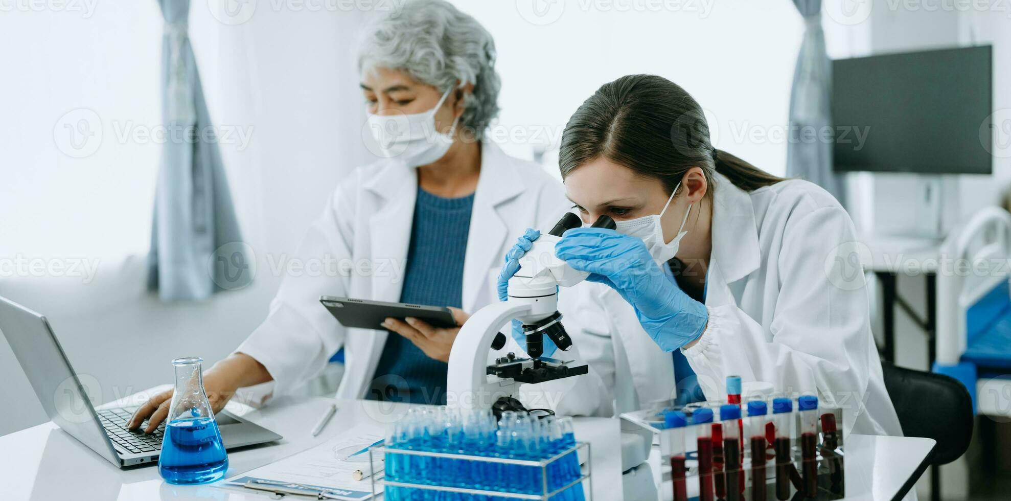 Two scientist or medical technician working, having a medical discuss meeting with an Asian senior female scientist supervisor in the laboratory with online reading, test samples and innovation photo