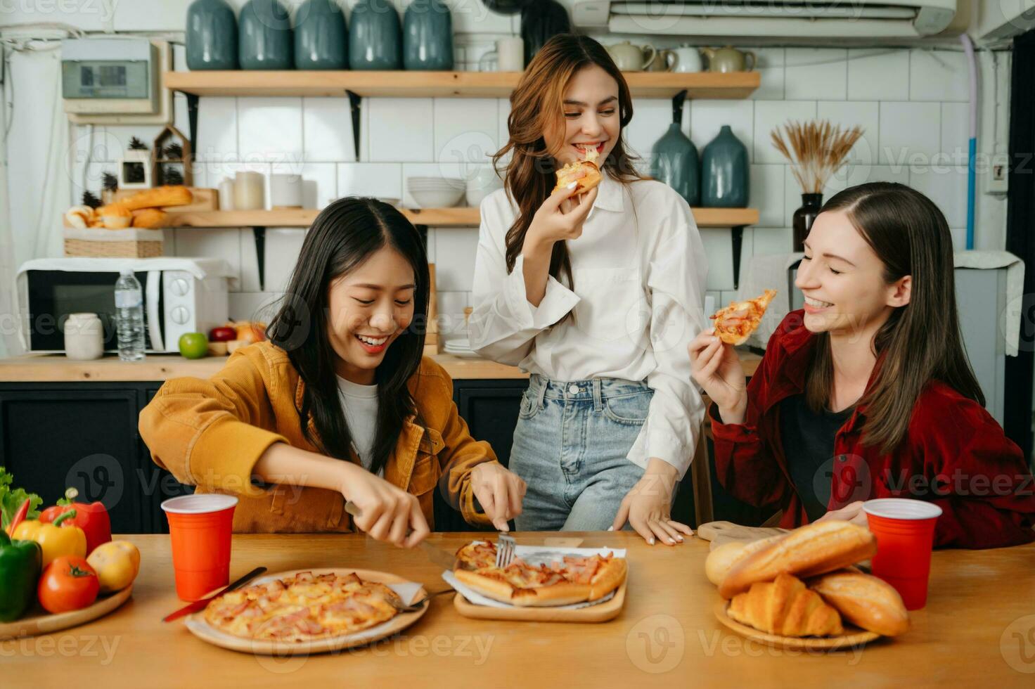 Group of friends making fun at home party.They sitting on desk in living room and eating pizza. happy photo