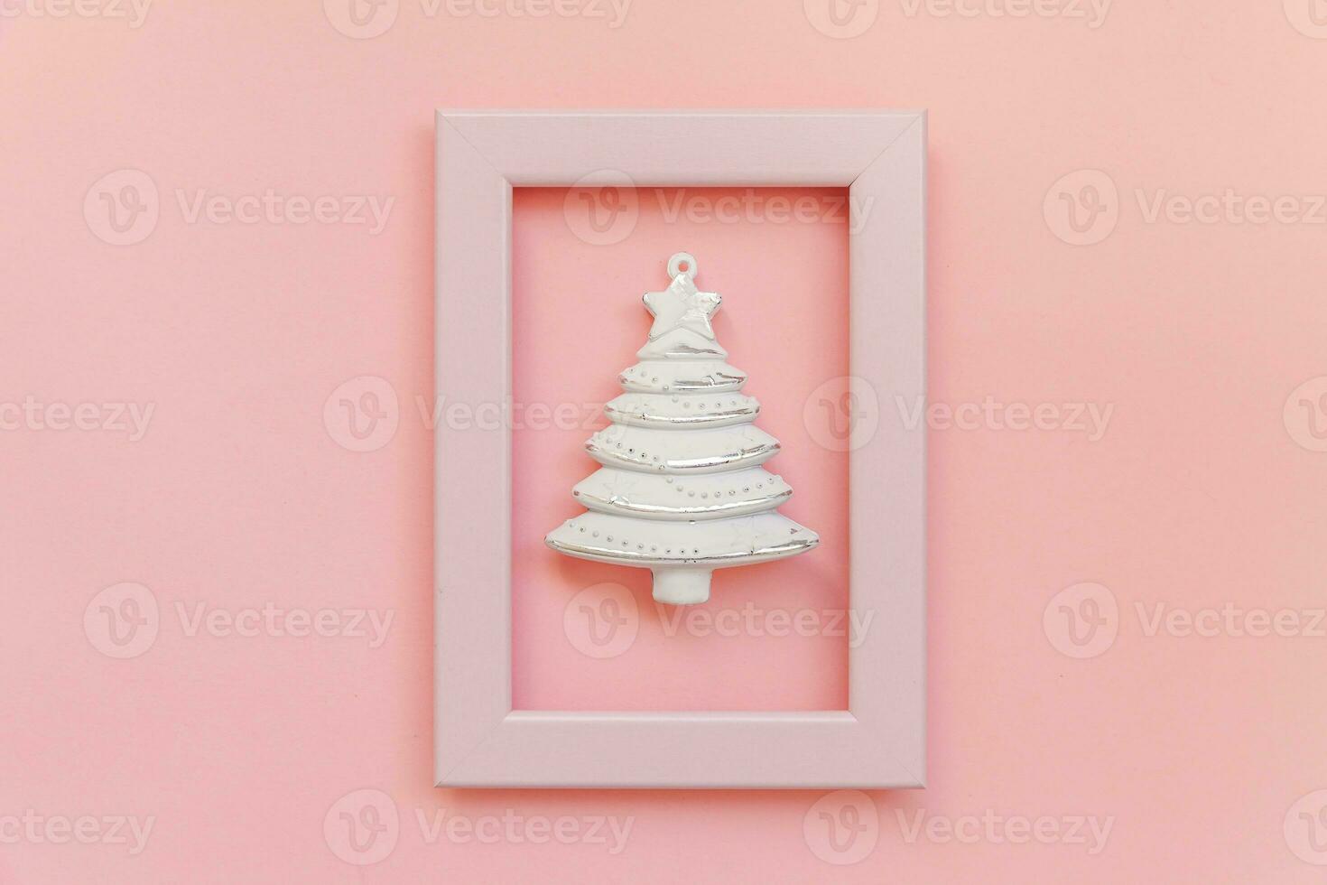Simply minimal composition winter objects ornament fir tree in pink frame isolated on pink pastel trendy background photo