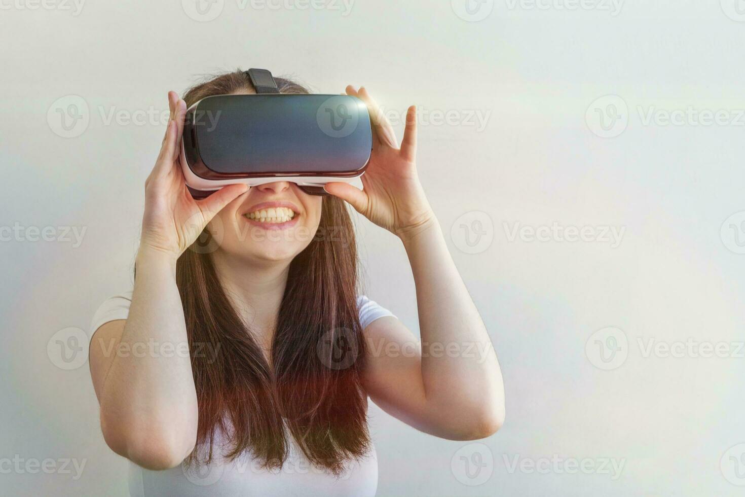 Smile young woman wearing using virtual reality VR glasses helmet headset on white background. Smartphone using with virtual reality goggles. Technology, simulation, hi-tech, videogame concept. photo