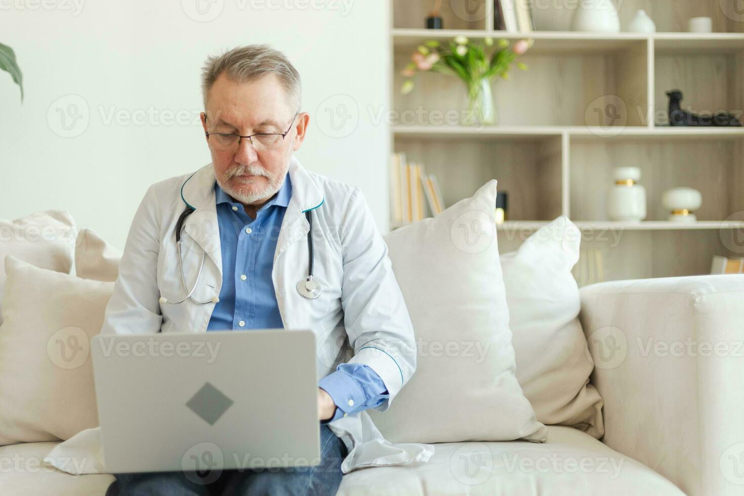 mayor hombre médico trabajando con ordenador portátil computadora. profesional mayor maduro cuidado de la salud experto buscando información o tener consulta en línea en hospital habitación. medicina cuidado de la salud médico chequeo. foto