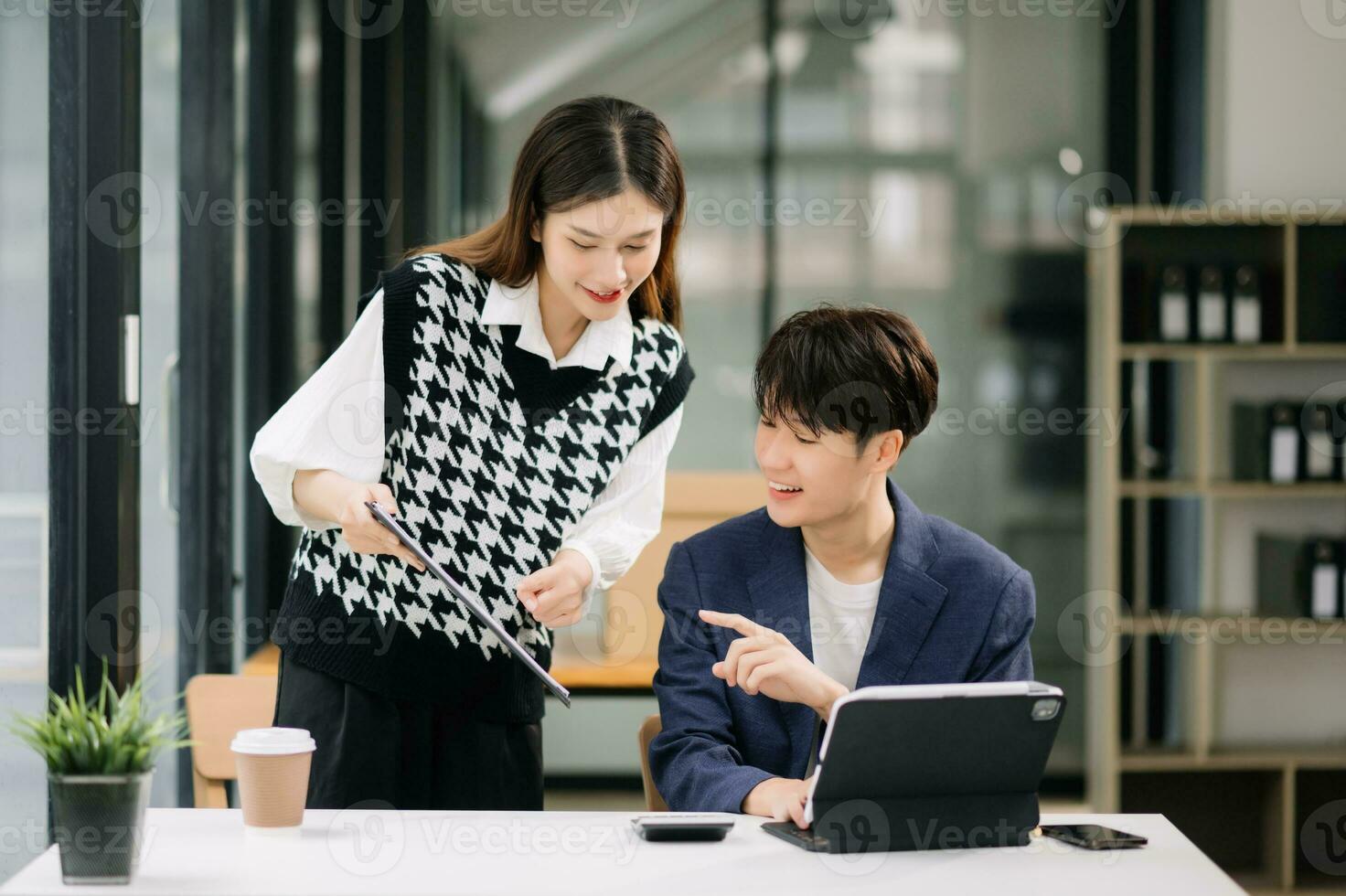 Two Asian business workers talking on the smartphone and using laptop at the modern office. photo