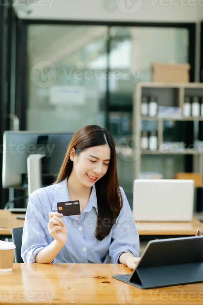Asian Woman using smart phone for mobile payments online shopping,omni channel,sitting on table,virtual icons graphics interface screen in morning light photo