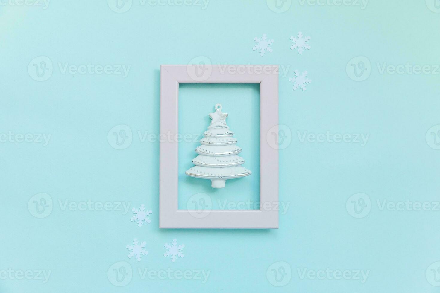Simply minimal composition winter objects ornament fir tree in pink frame isolated on blue pastel trendy background photo