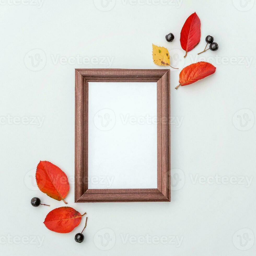 Autumn floral composition. Vertical photo frame mockup chokeberry rowan berries colorful leaves on white background. Fall natural plants ecology fresh wallpaper concept. Flat lay top view, copy space