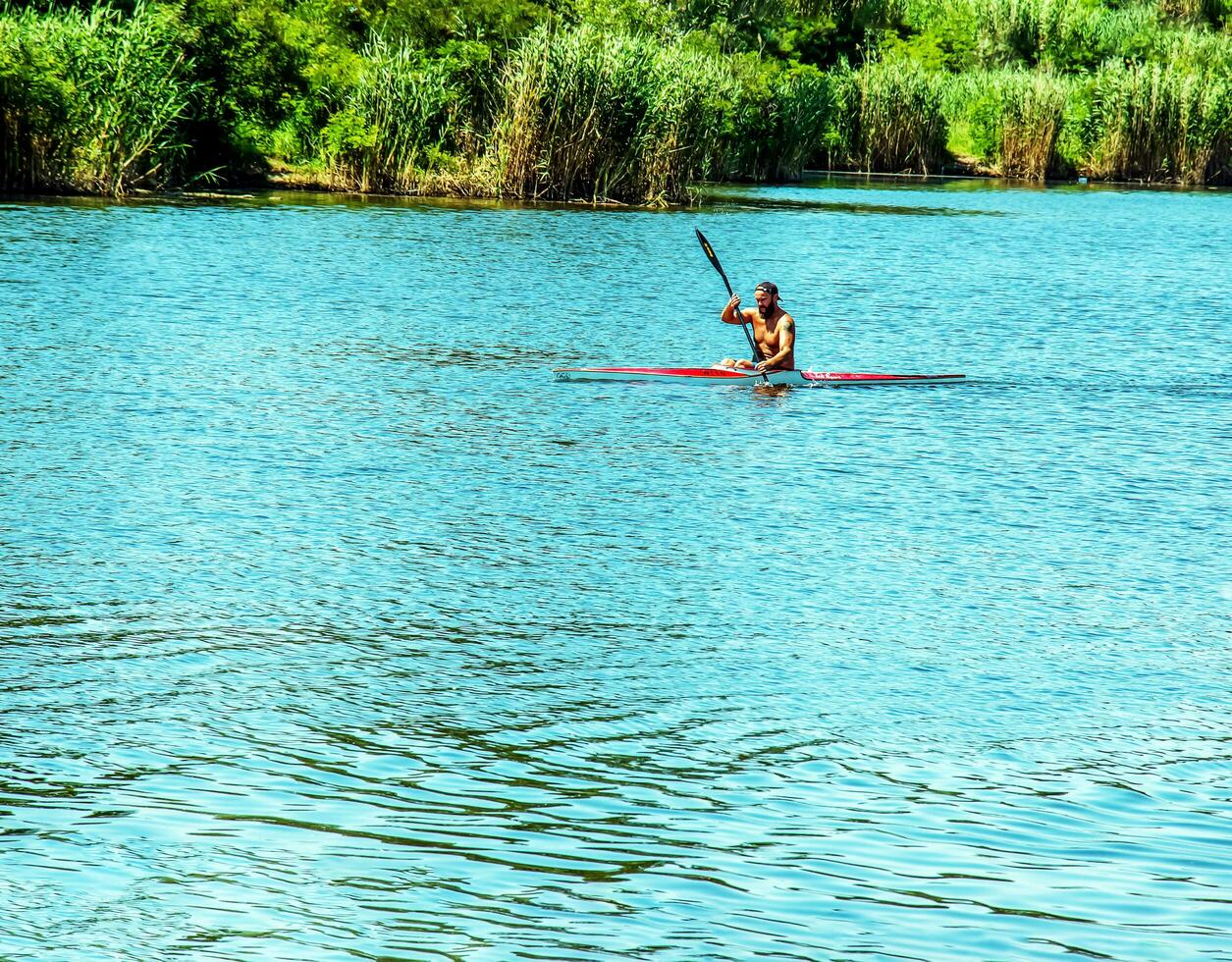 Dnipro, Ukraine - 06.20.2023 Technique of rowing of a single athlete on a kayak. Paddle splash motion. photo