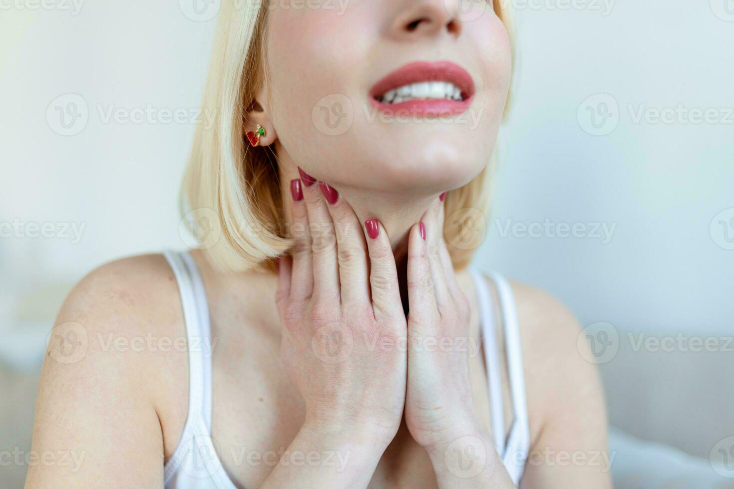 Close up of young woman rubbing her inflamed tonsils, tonsilitis problem, cropped. Woman with thyroid gland problem, touching her neck, girl has a sore throat photo