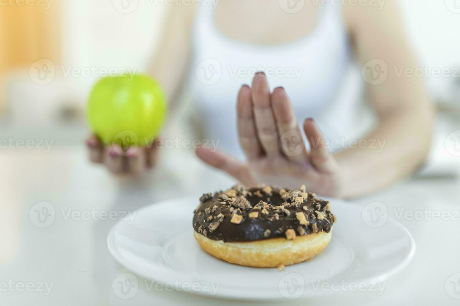 Dieting or good health concept. Young woman rejecting Junk food or unhealthy food such as donut or dessert and choosing healthy food such as fresh fruit or vegetable. photo