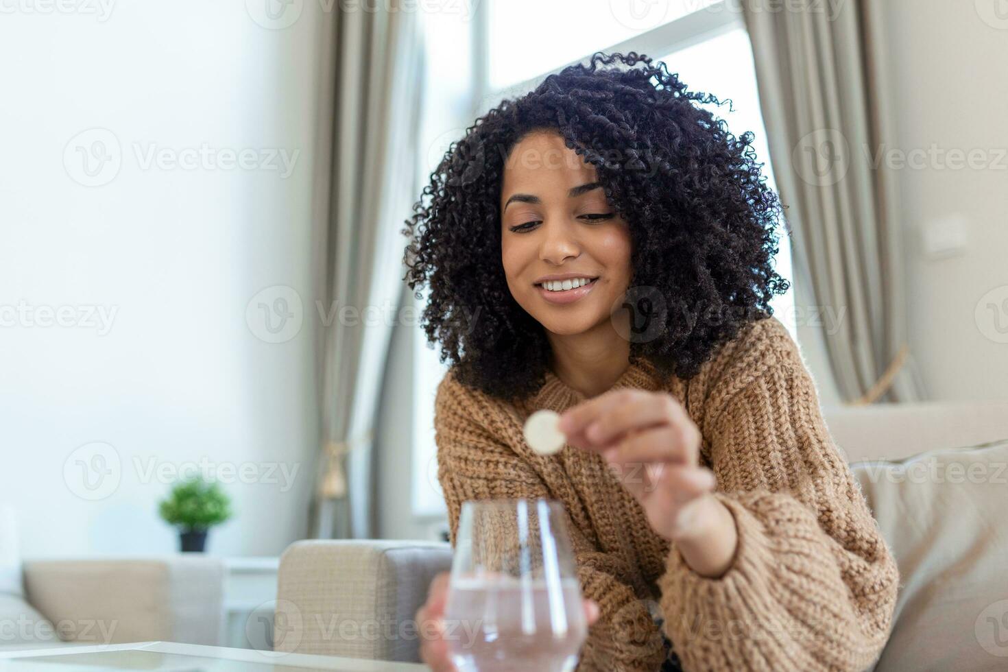 Closeup of a young woman dropping an effervescent antacid in a glass of