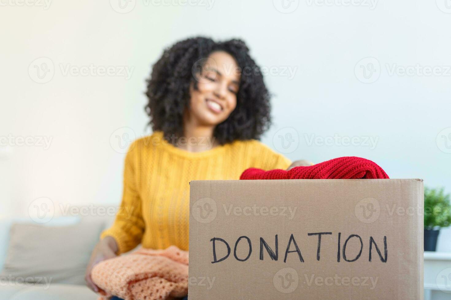 Donation Concept. Woman holding a Donate Box with full of Clothes. Woman holding a book and clothes donate box. Clothes in box for concept donation and reuse recycle photo