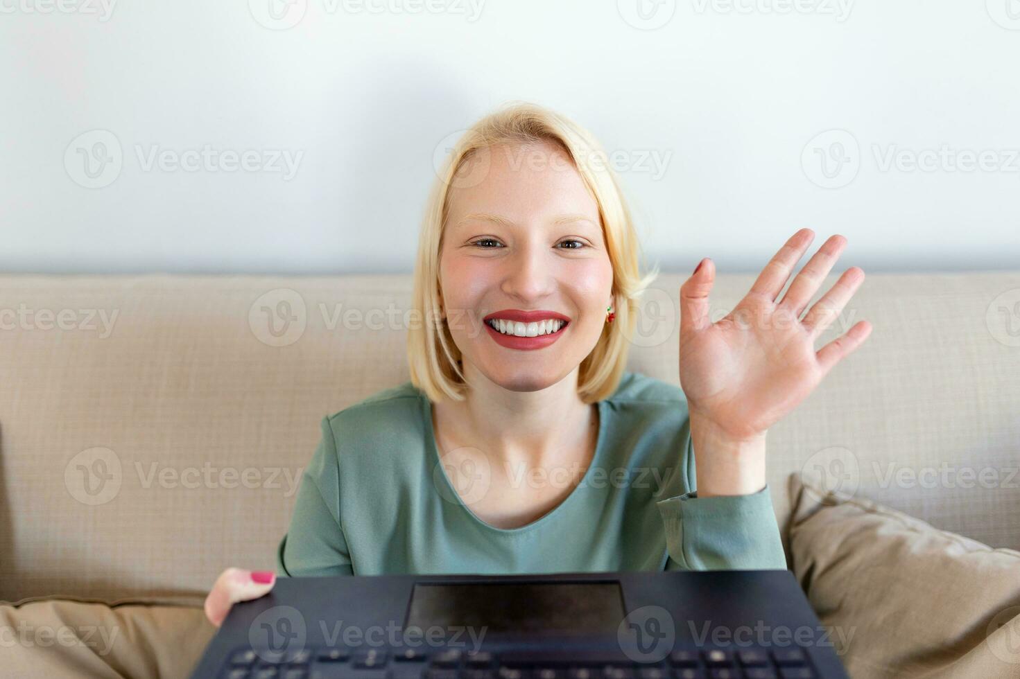 Young woman waving at laptop and talking to her friends via video call, girl student talking by video conference call, female teacher trainer tutoring by webcam, online training, e-coaching concept photo