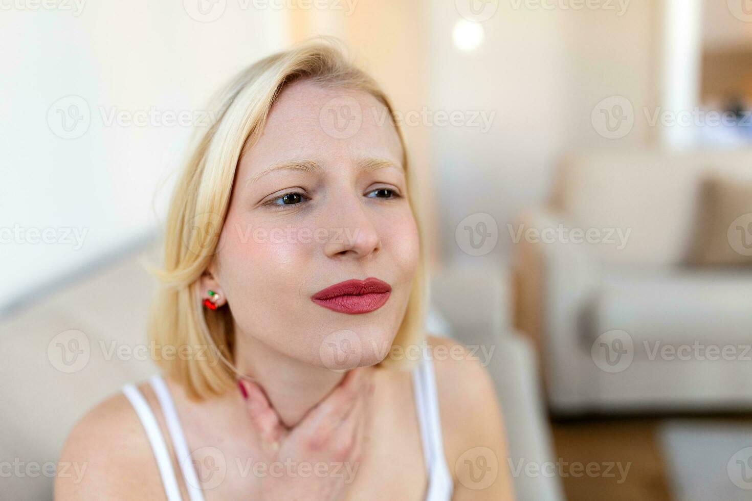 Young beautiful woman suffering from pain in throat, touching inflamed zone on her neck, cropped, empty space, sore throat photo