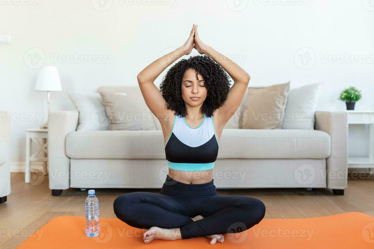 Young attractive smiling woman practicing yoga, sitting in Half Lotus exercise, Ardha Padmasana pose, working out, wearing sportswear, meditation session, indoor full length, home interior photo