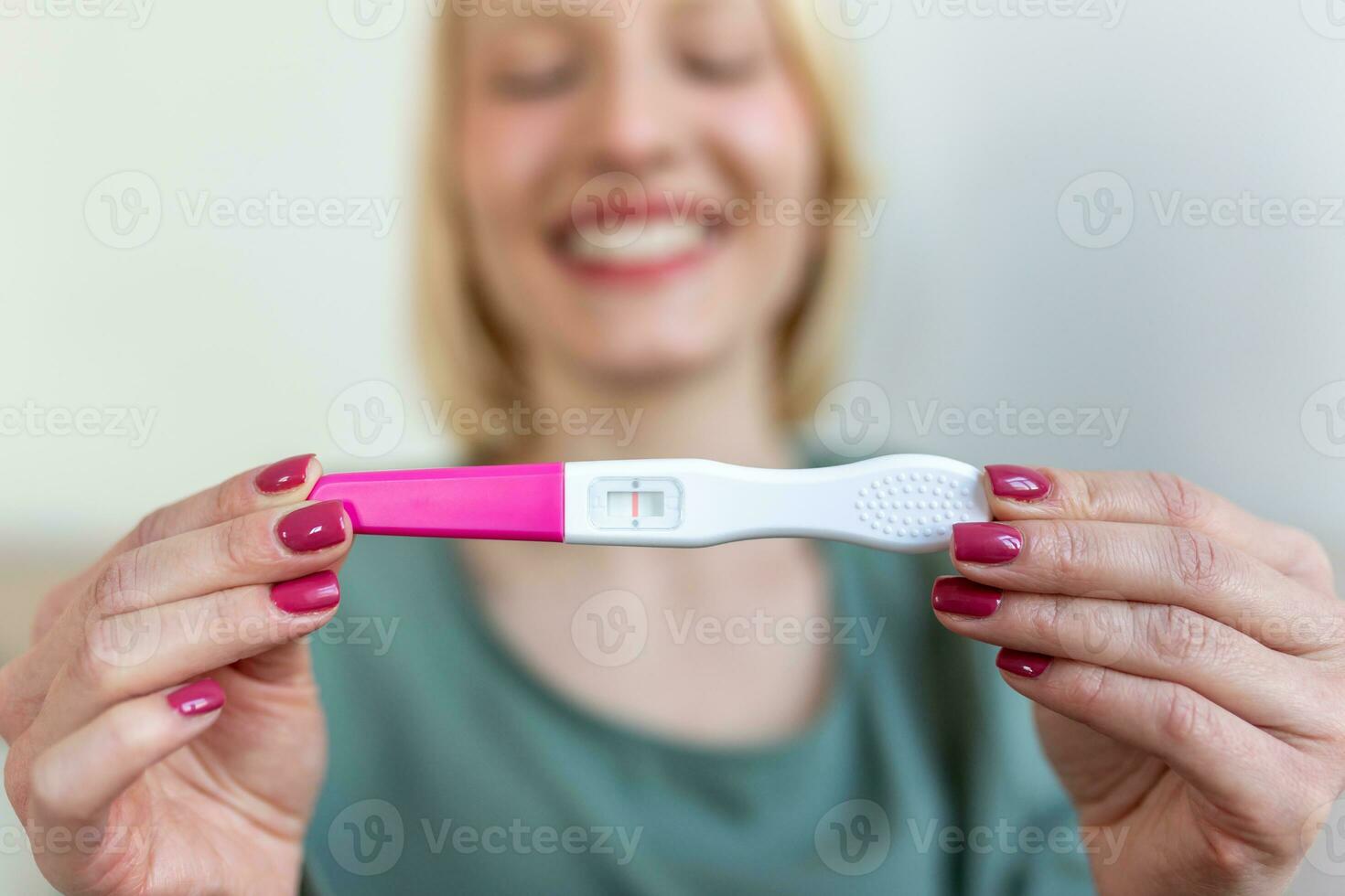 Pregnancy, fertility, maternity and people concept - happy smiling woman looking at pregnancy test at home photo
