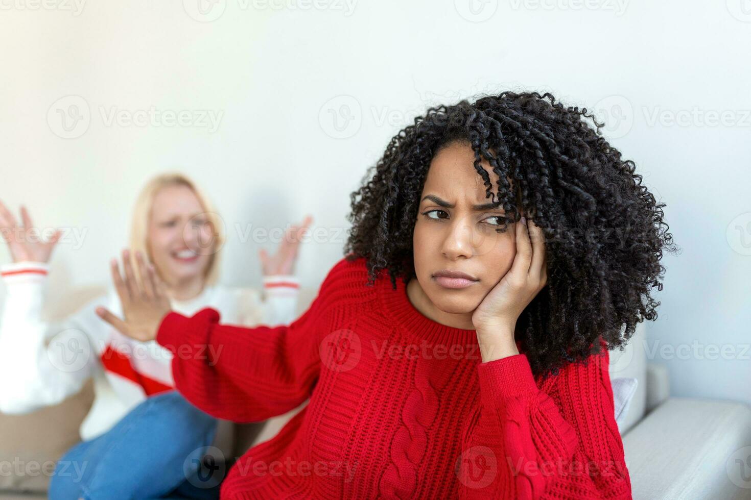 Dont want to hear. Unhappy disturbed tired woman communicating with her friend sitting near her on the sofa shaking her hands. Friends arguing on sofa at home. Two female friends arguing photo