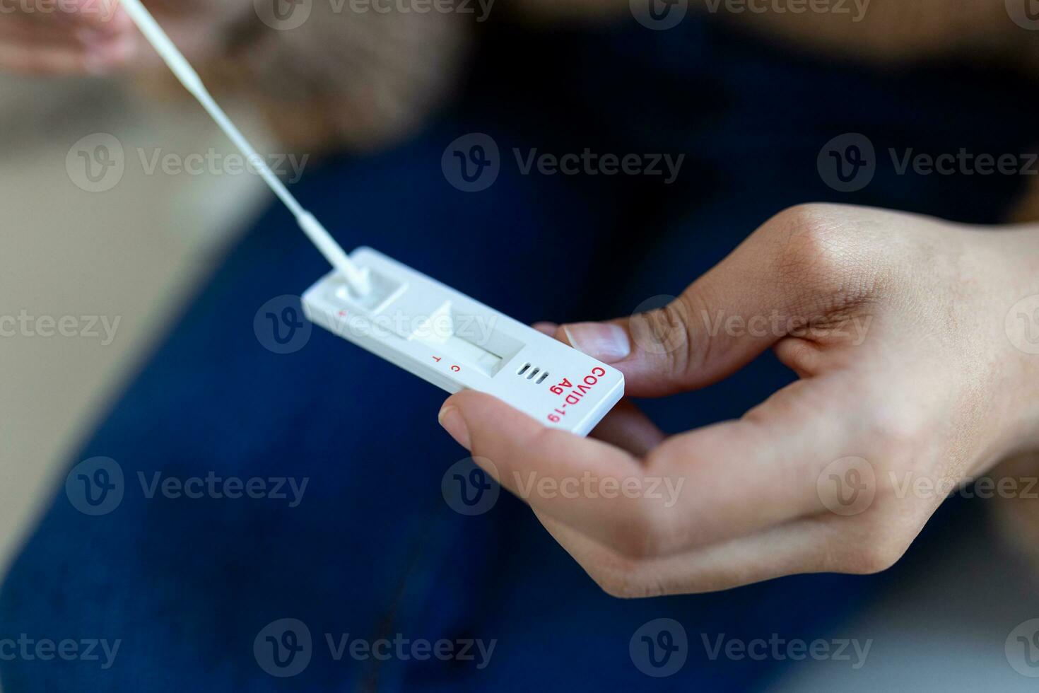 African-American woman using cotton swab while doing coronavirus PCR test at home. Woman using coronavirus rapid diagnostic test. Young woman at home using a nasal swab for COVID-19. photo