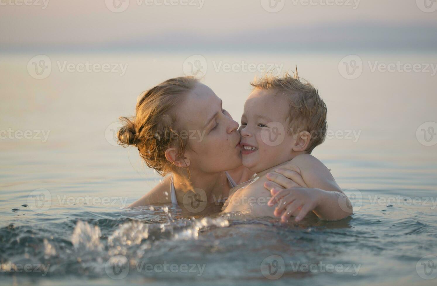 Mother playing in the sea with her little son photo