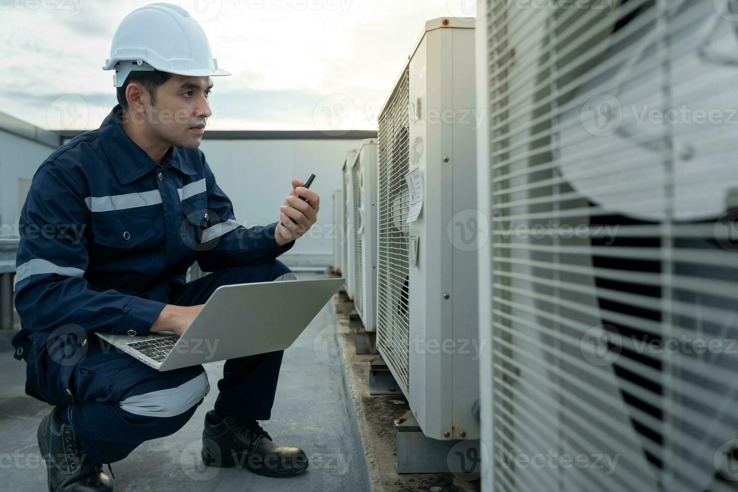 Asian maintenance engineer work on the roof of factory. contractor inspect compressor system and plans installation of air condition systems in construction. technology, walky talky, maintenance photo