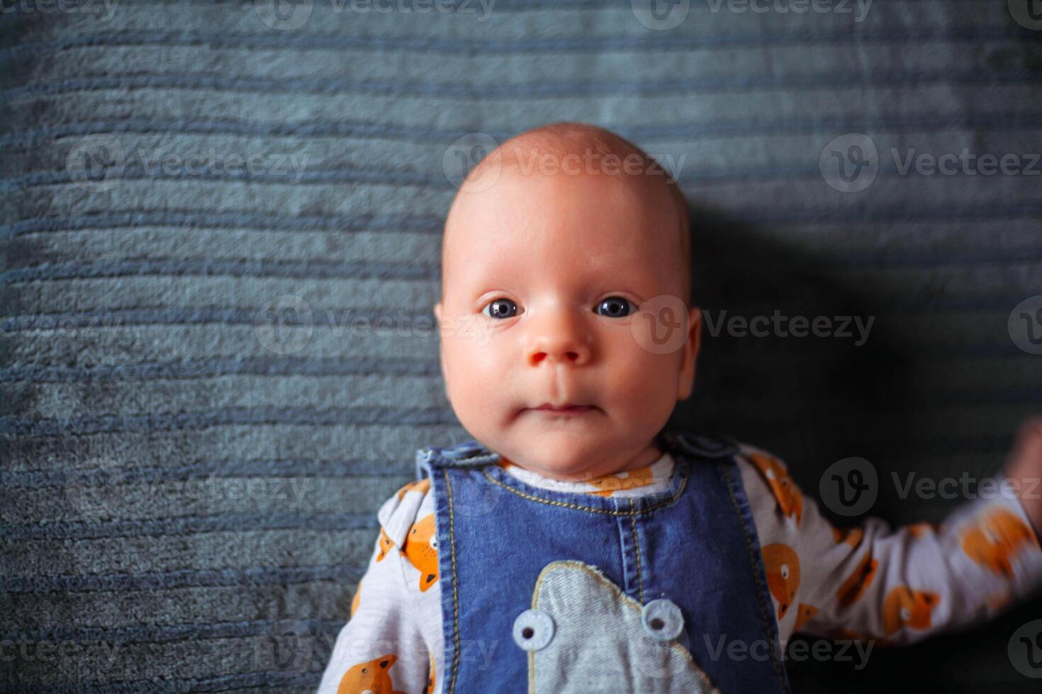 Little boy, newborn, with beautiful blue eyes looks at the camera photo