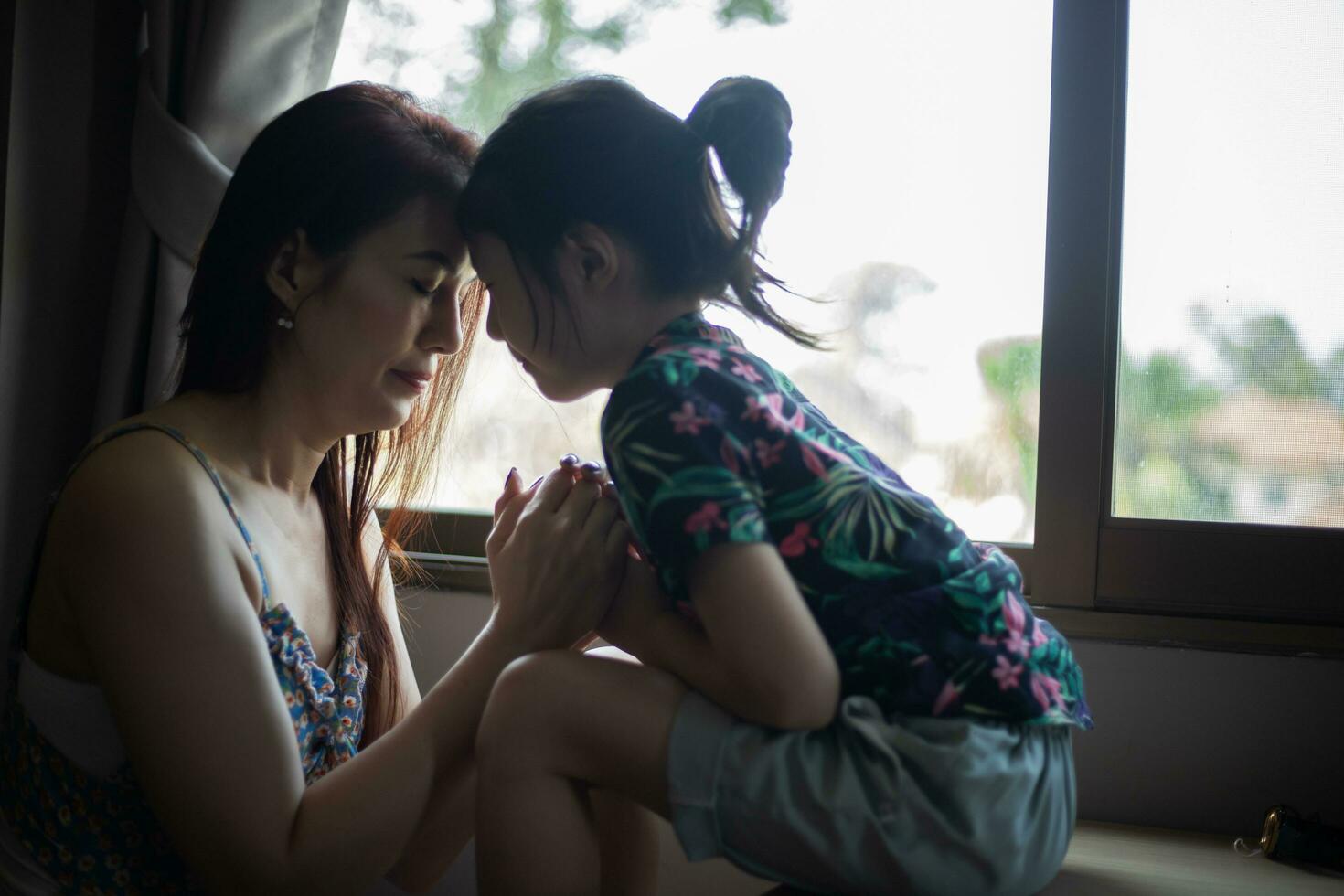 Mother teaching her daughter to praying at home. photo