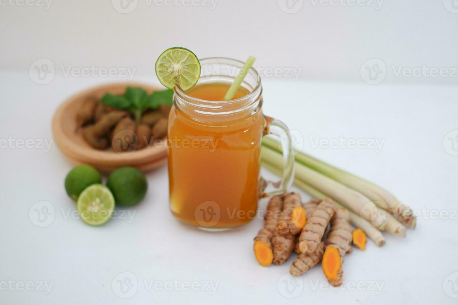 Fresh ginger and lemon juice in a glass jar with ginger roots on white background. photo