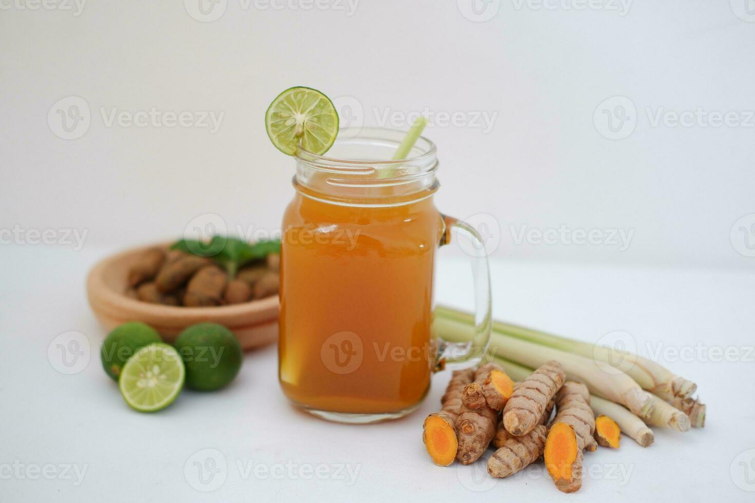 Fresh ginger and lemon juice in a glass jar with ginger roots on white background. photo