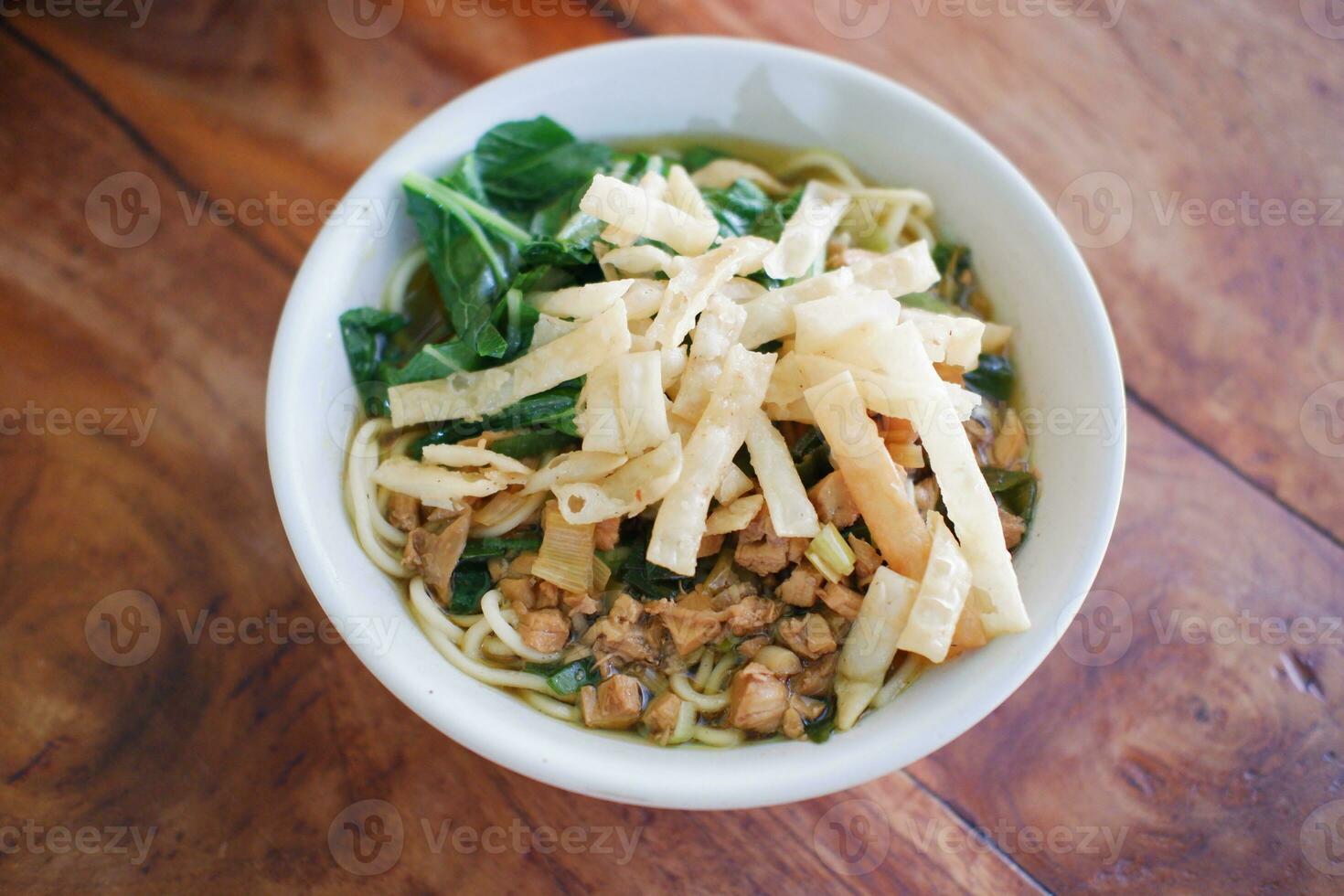 Fried noodle in white bowl on wooden table photo