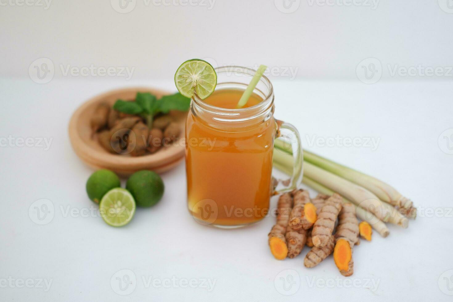 Fresh ginger and lemon juice in a glass jar with ginger roots on white background. photo